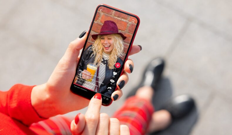 Persoană care ține în mână un telefon cu un video tiktok pe ecran, pentru a ilustra ce e un NPC
